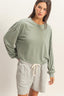 Woman wearing a green oversized sweatshirt and gray shorts on a white background