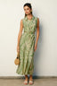 Woman wearing a green patterned dress against a white wall
