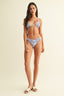 Woman wearing a blue floral bikini set on a beige background