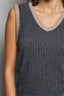 Close-up of a person wearing a ribbed tank top with a neutral trim against a gray background