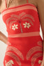 Red dress with palm tree and flower patterns on a beige background