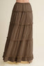 A brown tiered maxi skirt with ruffled trim, shown on a model against a light beige background.