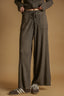 Person wearing brown ribbed pants and shoes on a beige background