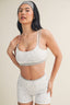 Woman wearing a light gray sports bra and shorts set on a beige background