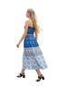 Woman in a blue and white dress walking on a sidewalk with people and tents in the background
