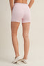 Person wearing light pink patterned shorts on a beige background