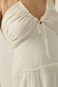 Close-up of a white dress with ruched details on a plain background