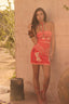 Woman in a red dress standing against a beige wall with desert-like background