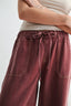 Maroon wide-leg pants with a white top on a plain background