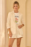 Woman wearing a beige blazer over a floral t-shirt with a plain background