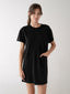 Woman wearing a black t-shirt dress against a white background