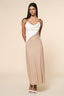 Woman wearing a two-tone dress with a white top and beige skirt on a beige background