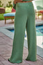 Green textured pants worn by a person standing by a poolside.