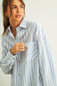 Woman wearing a light blue and white striped shirt against a plain background