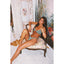 Woman in a green bikini sitting on a floral chair in a decorated room.