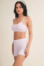 Woman wearing a matching sports bra and shorts set on a beige background