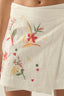 Beige skirt with colorful floral embroidery on a neutral background