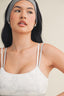 Woman wearing a white tank top and gray headband against a neutral background