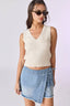 Woman wearing a cream sleeveless top and denim skirt on a white background