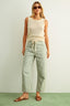 Woman wearing a sleeveless top and striped pants against a plain background