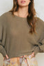 Woman wearing a brown sweater with a neutral background