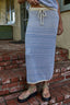 Person wearing a blue and white striped skirt on a brick porch.