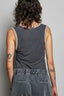 Person wearing a sleeveless gray top with beige straps against a plain background