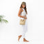 Woman in white outfit holding a beige bag on a white background