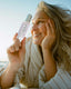 Woman holding a bottle of OSEA product by the beach