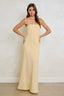 Woman wearing a strapless beige gown against a plain background