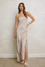 Woman wearing a strapless, patterned gown with a slit on a plain background