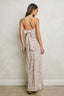 Woman wearing a beige strapless dress with a pattern against a plain wall.