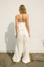 Person wearing a white jumpsuit standing against a plain wall.