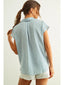 Woman wearing a light blue sleeveless shirt and white shorts on a plain background