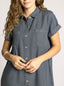Woman wearing a blue denim dress with short sleeves on a plain background