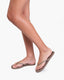 Person wearing beige flip-flops on a white background