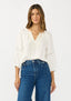 Woman wearing a white blouse and blue jeans on a plain background