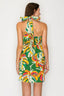 Woman wearing a colorful halter neck dress with a banana leaf pattern on a white background