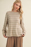 Woman wearing a striped sweater and brown pants against a beige background