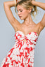 Woman wearing a red and white floral dress against a gray background