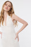 Woman wearing a white sleeveless dress against a plain background