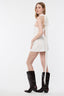 Woman wearing a white dress with a long train and black knee-high boots on a white background