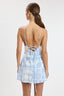 Woman wearing a blue and white patterned dress with thin straps on a plain background