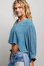 Woman wearing a blue denim top and jeans against a plain background