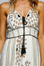 White dress with black floral patterns and tassel detail on a person