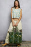 Woman wearing a floral top and patterned pants against a gray wall.