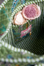 Decorative basket with pink and beige fabric flowers on a green textured background