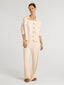 Woman wearing a beige outfit with a jacket and pants on a white background
