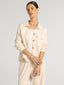 Woman wearing a beige outfit with a plain background