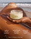 OSEA body butter jar held by a person on a beach with text highlighting benefits.